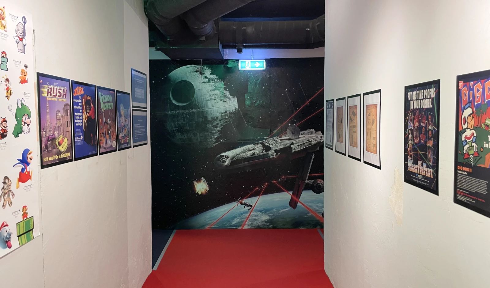 Pasillo con un mural de Star Wars, pósters de videojuegos enmarcados y una alfombra roja