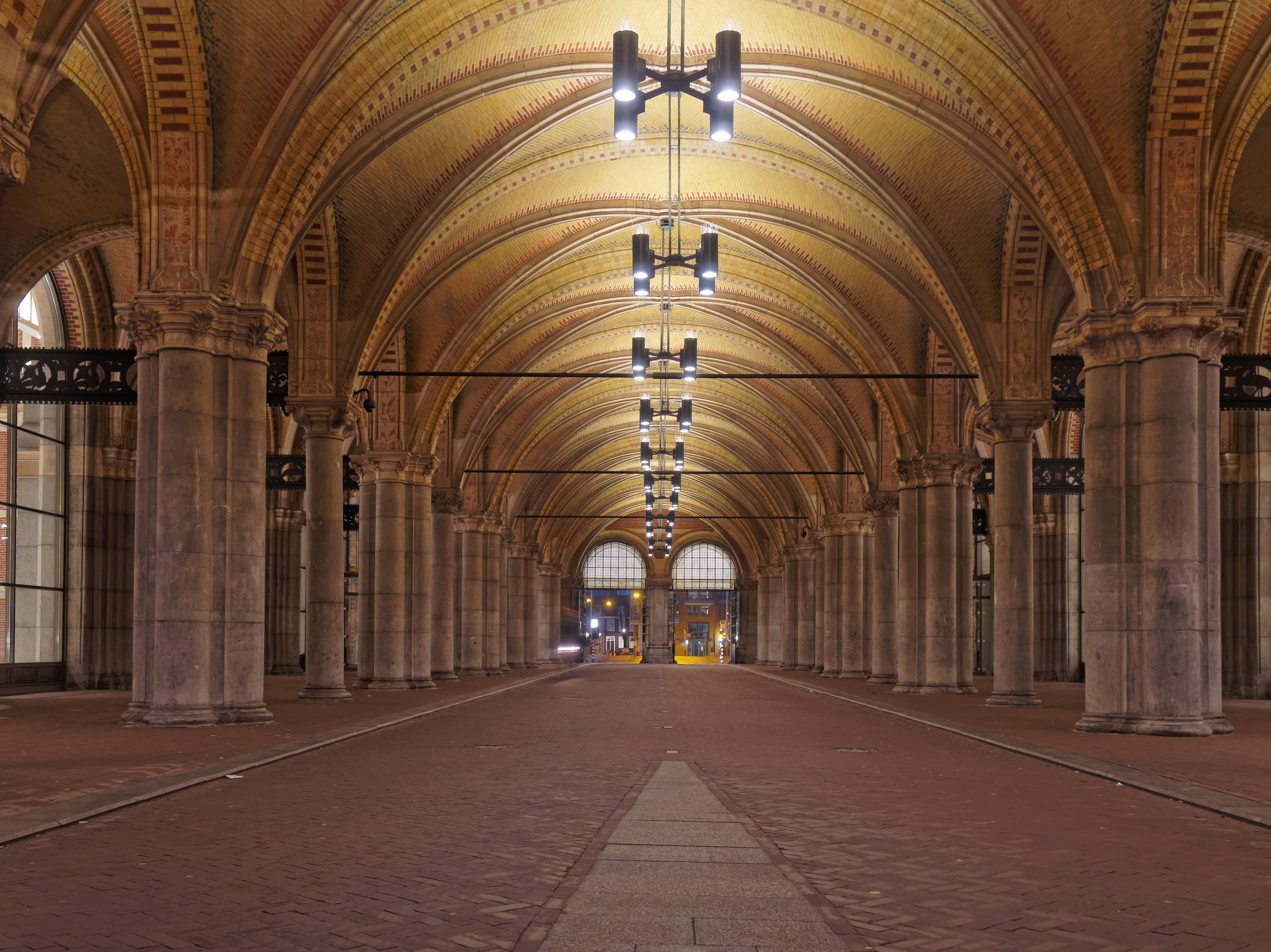 Lange gang met gewelfde plafonds en stenen zuilen in het Rijksmuseum