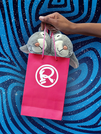 Bolsa de regalo rosa con el logo 'R' de Ripley's sosteniendo dos juguetes de peluche grises con forma de animal sobre un fondo con patrón de espiral azul