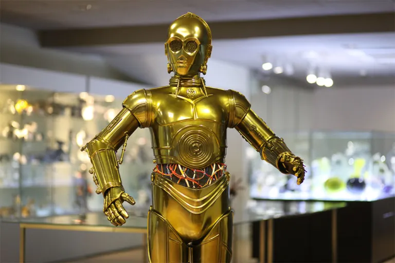 Gouden humanoïde robot met ingewikkeld mechanische details te zien in een museumgalerij