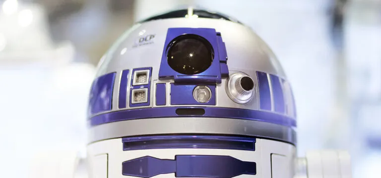 Close-up van een zilveren en blauwe robot met een koepelvormige kop en diverse panelen en sensoren