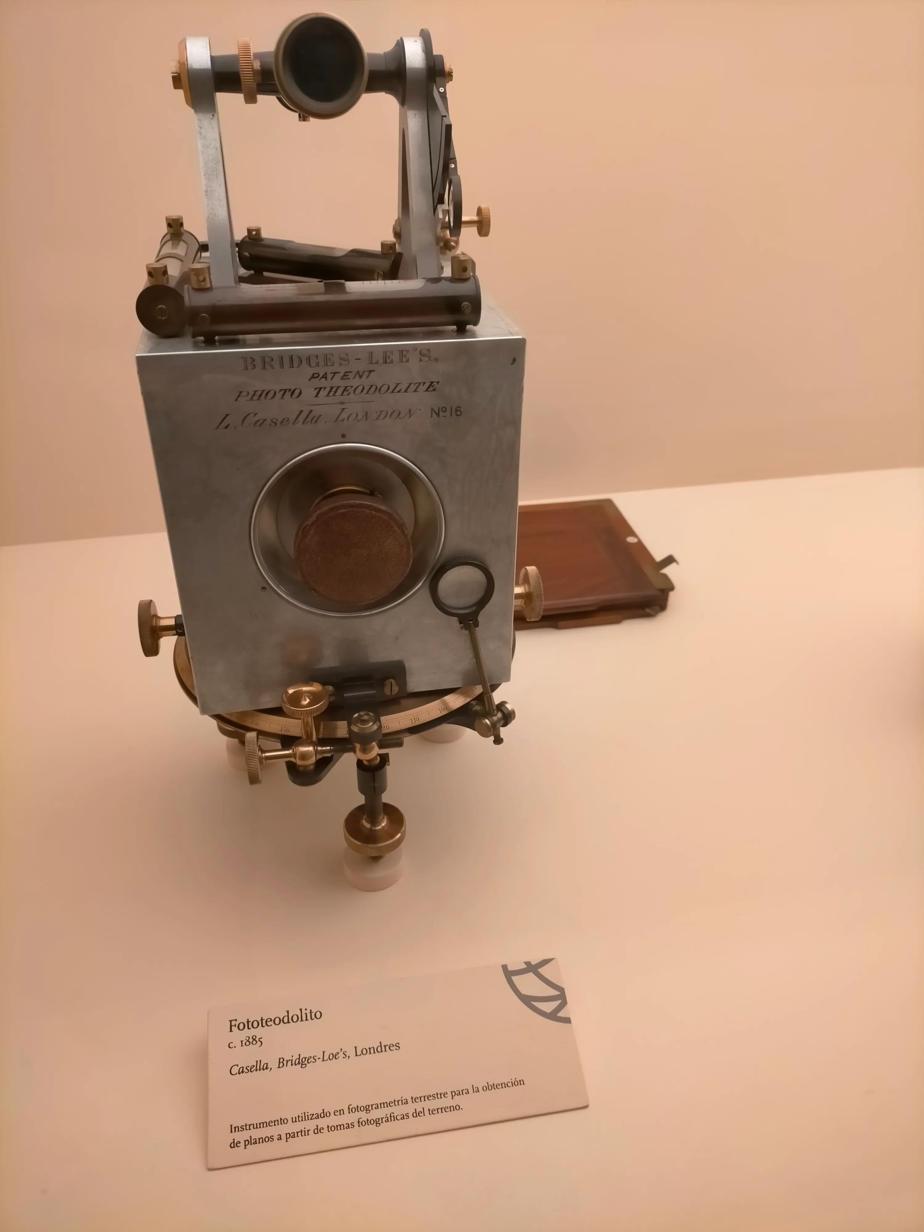 Instrument fototeodolitu w stylu vintage na białej powierzchni wystawowej z opisową tabliczką z przodu