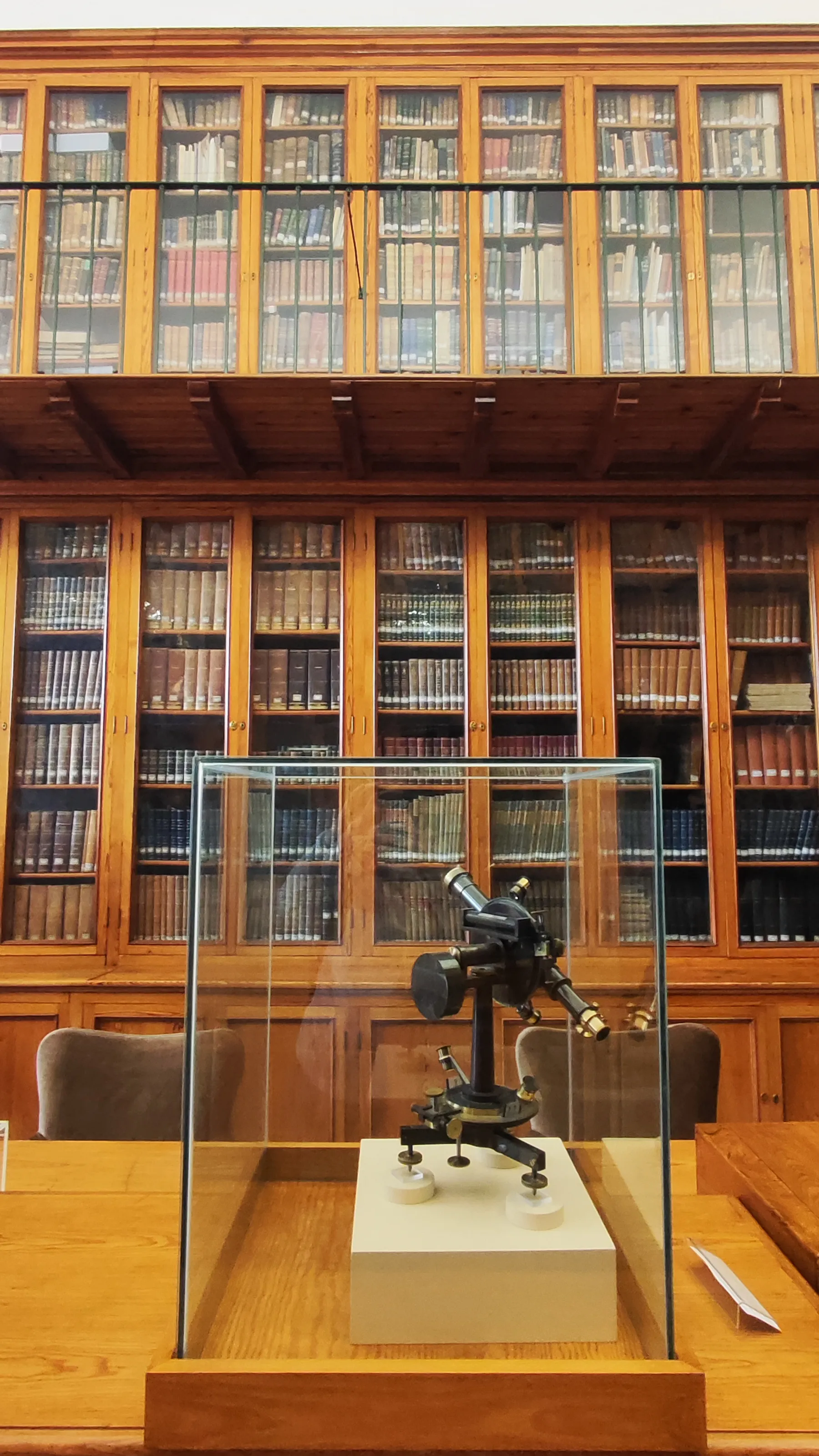 Wikteleskop w szklanej gablocie w bibliotece z drewnianymi regałami