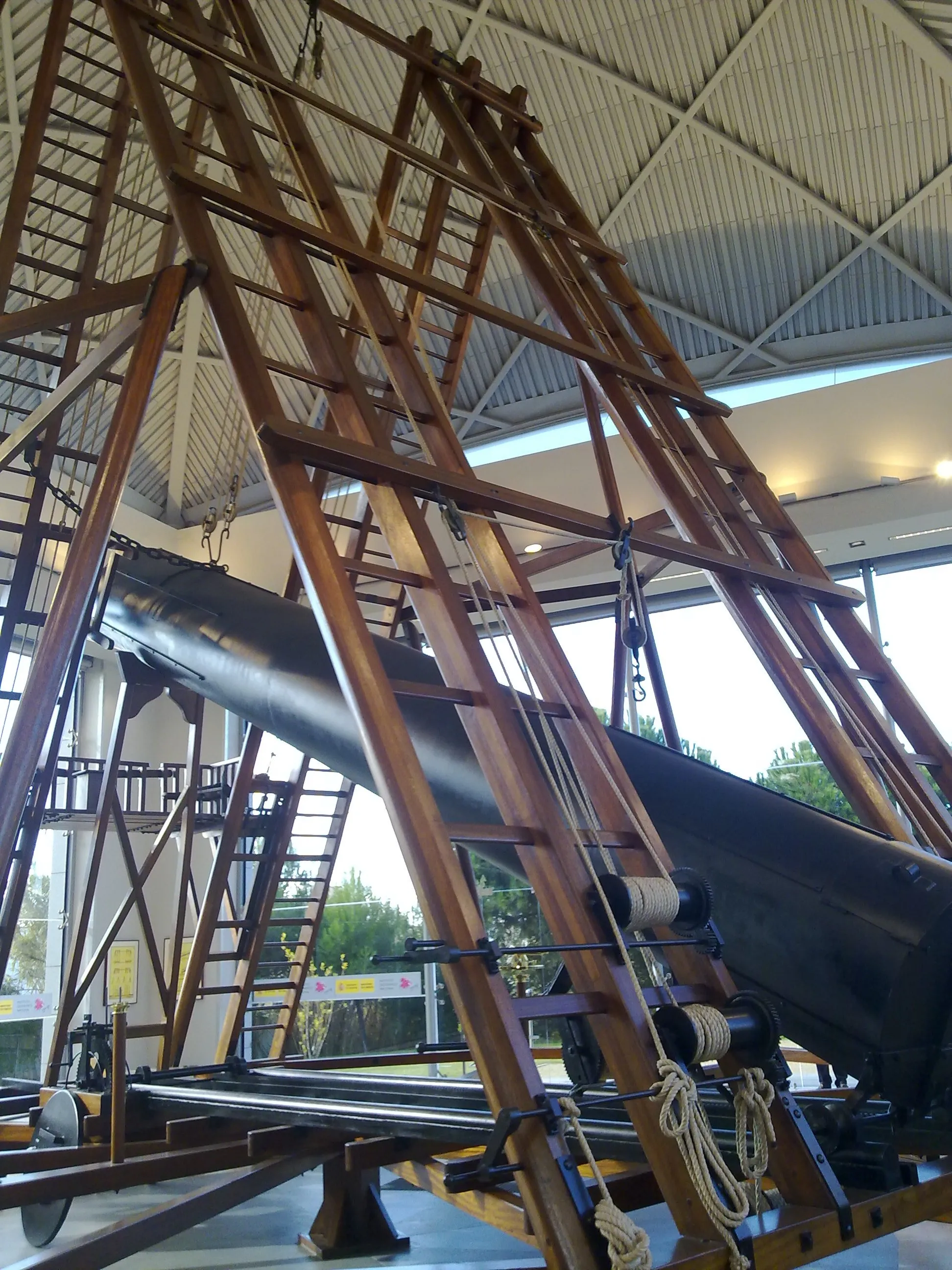 Duży zabytkowy teleskop z drewnianą konstrukcją wsporczą w muzeum
