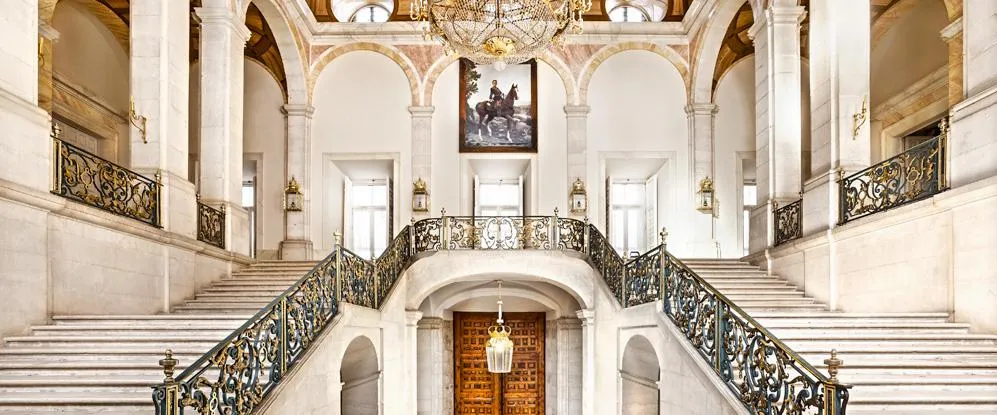 Gran escalera con barandillas ornamentadas y candelabro en el Palacio Real de Aranjuez
