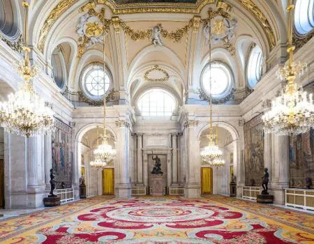 Siertuig van het Koninklijk Paleis van Madrid met kroonluchters, boogramen en een groot tapijt met patronen