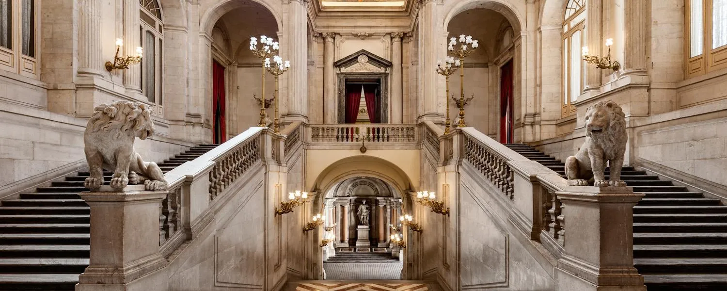 Grote binnentrap met stenen balustrades, twee leeuwenbeelden en booggangen in het Koninklijk Paleis van Madrid