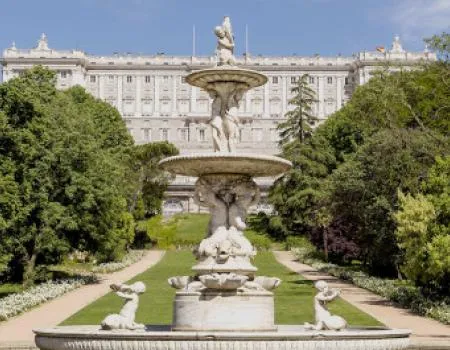 Een grote sierlijke fontein in een formele tuin met het Koninklijk Paleis van Madrid op de achtergrond