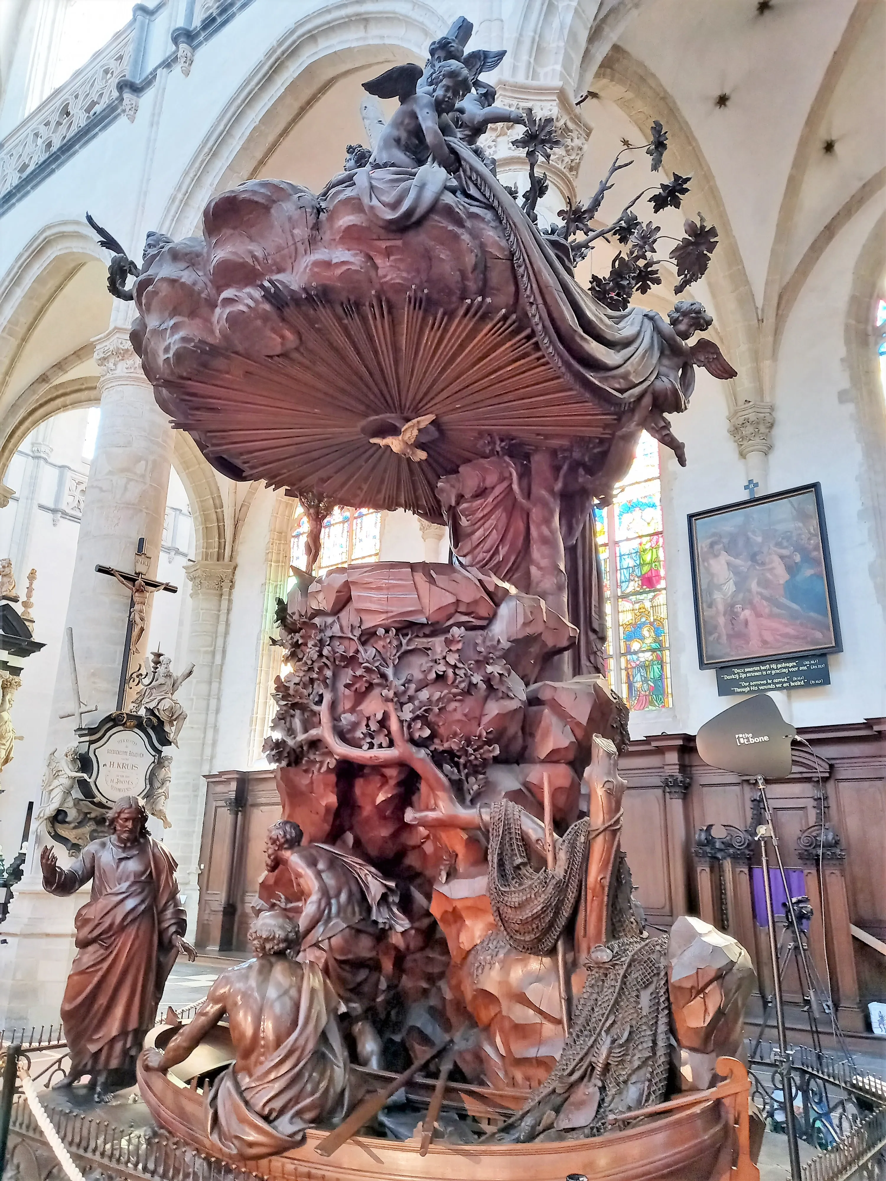 Púlpito de madera tallada ornamentada con figuras de ángeles y dosel de nubes dentro de la Iglesia de San Andrés, Amberes