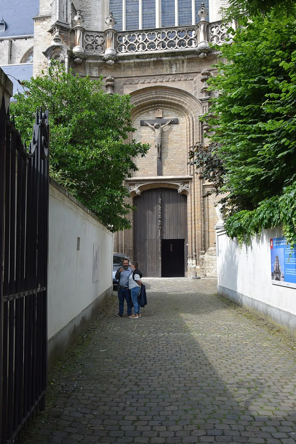Camino de adoquines que conduce a la gran puerta de madera de la Saint James' Church, con un crucifijo montado sobre la entrada y dos visitantes cerca