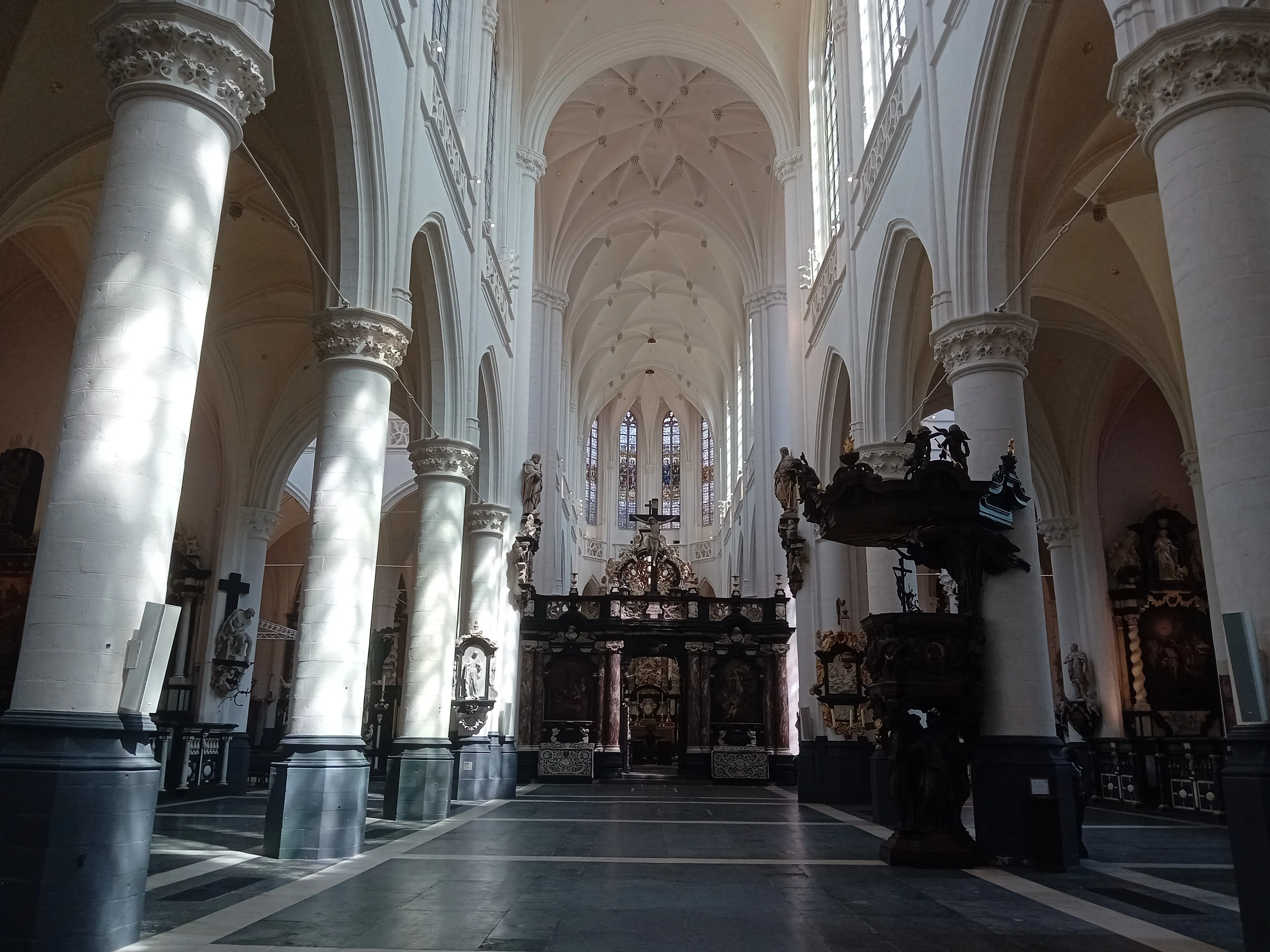Vista a lo largo de la nave de la St. James' Church, mostrando filas de grandes columnas blancas que sostienen un techo abovedado alto, con una estructura de madera oscura y ornamentada a la derecha.