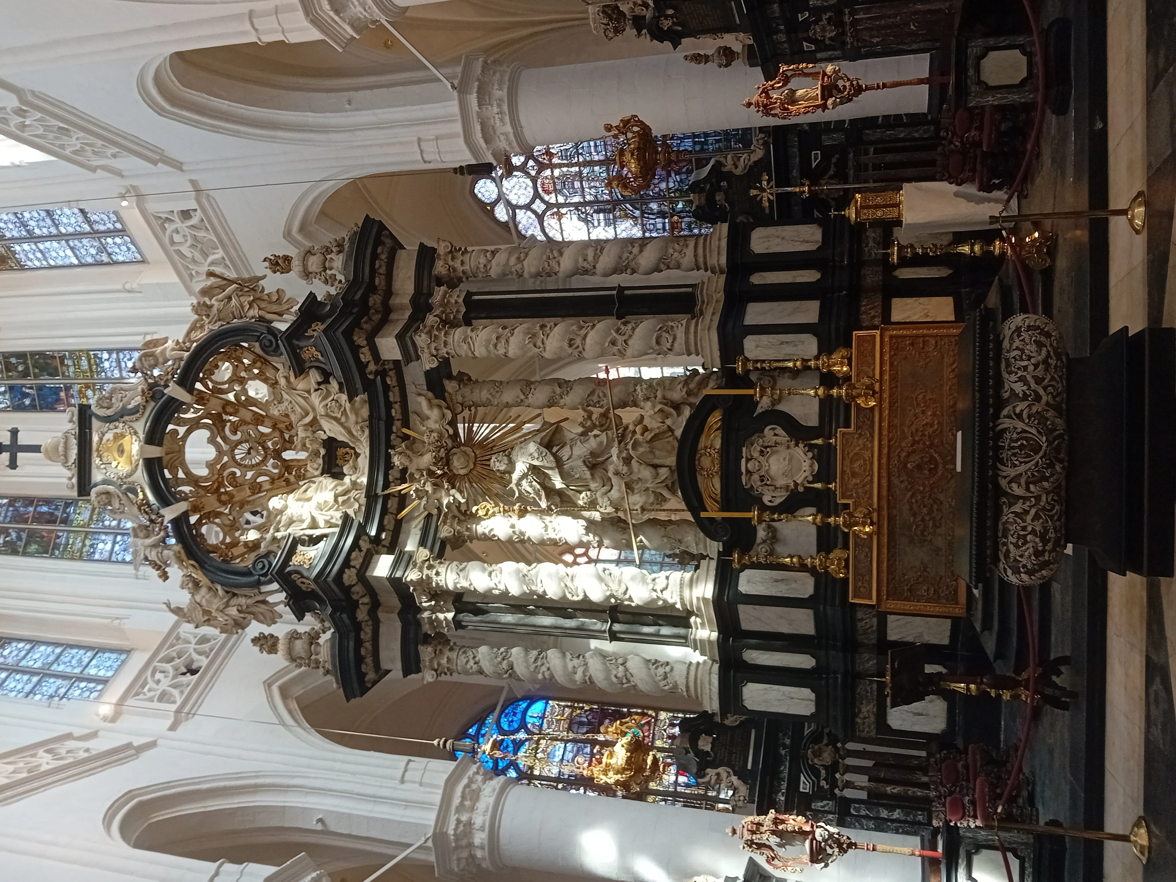 Ornado altar mayor barroco con columnas de mármol blanco y negro, decoraciones doradas y estatuaria religiosa dentro de la iglesia de Saint James
