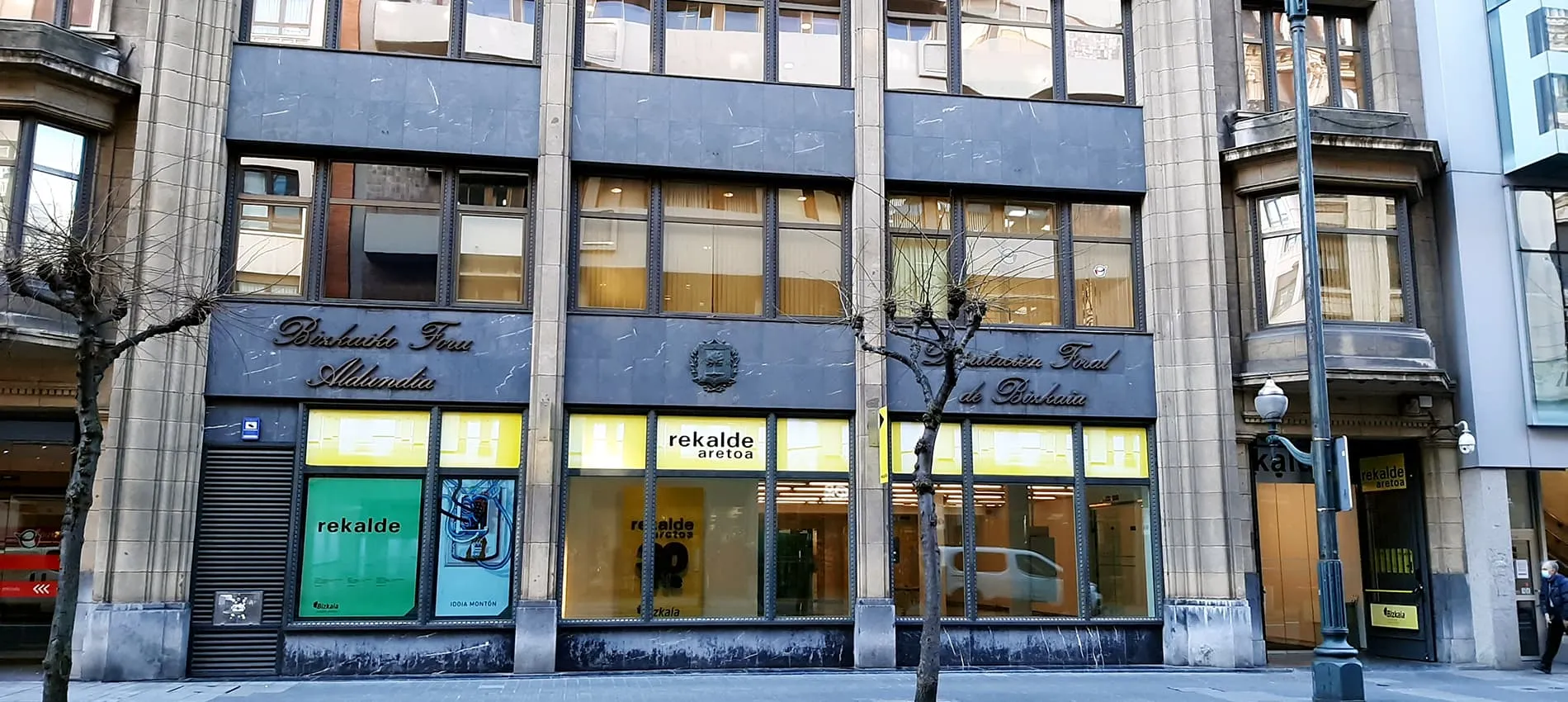 Street-level view of the Sala Rekalde building facade with illuminated storefront windows and visible signage on a city street