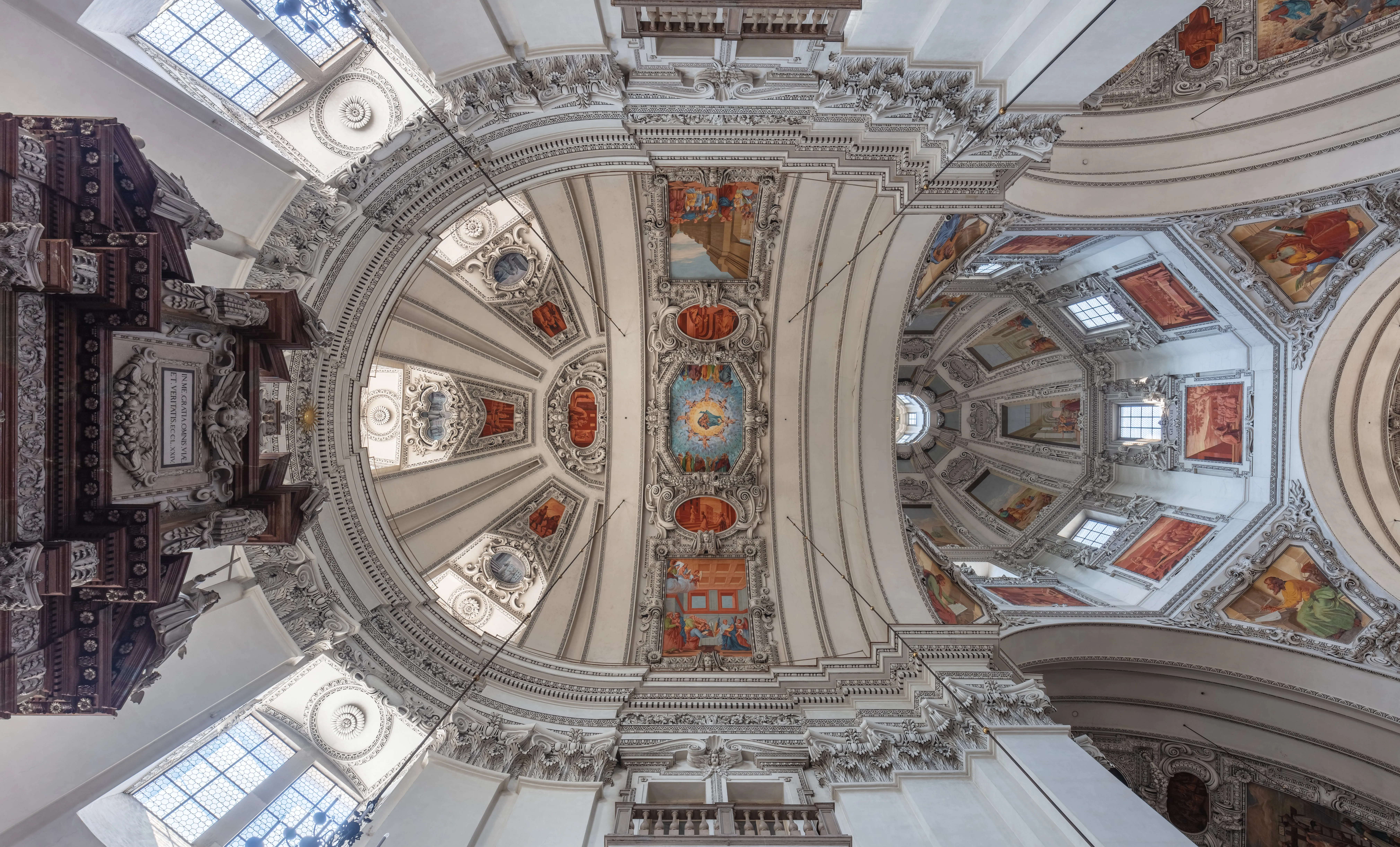 Interior de la cúpula y el ornamentado techo barroco de la Catedral de Salzburgo con frescos pintados, decoraciones de estuco blanco y ventanas arqueadas
