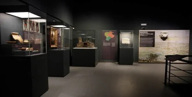 galería de museo oscura con vitrinas que contienen artefactos y un panel informativo en la pared