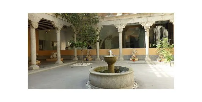 Patio con fuente de piedra rodeado de columnas y arcos