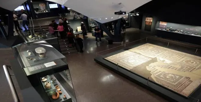 Interior del Museo de San Isidro con una gran exhibición de suelo de mosaico y vitrinas con artefactos