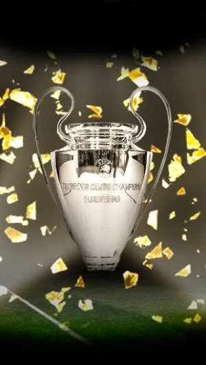 Srebrne trofeum Ligi Mistrzów UEFA ze złotymi konfetti spadającymi na zielone tło boiska