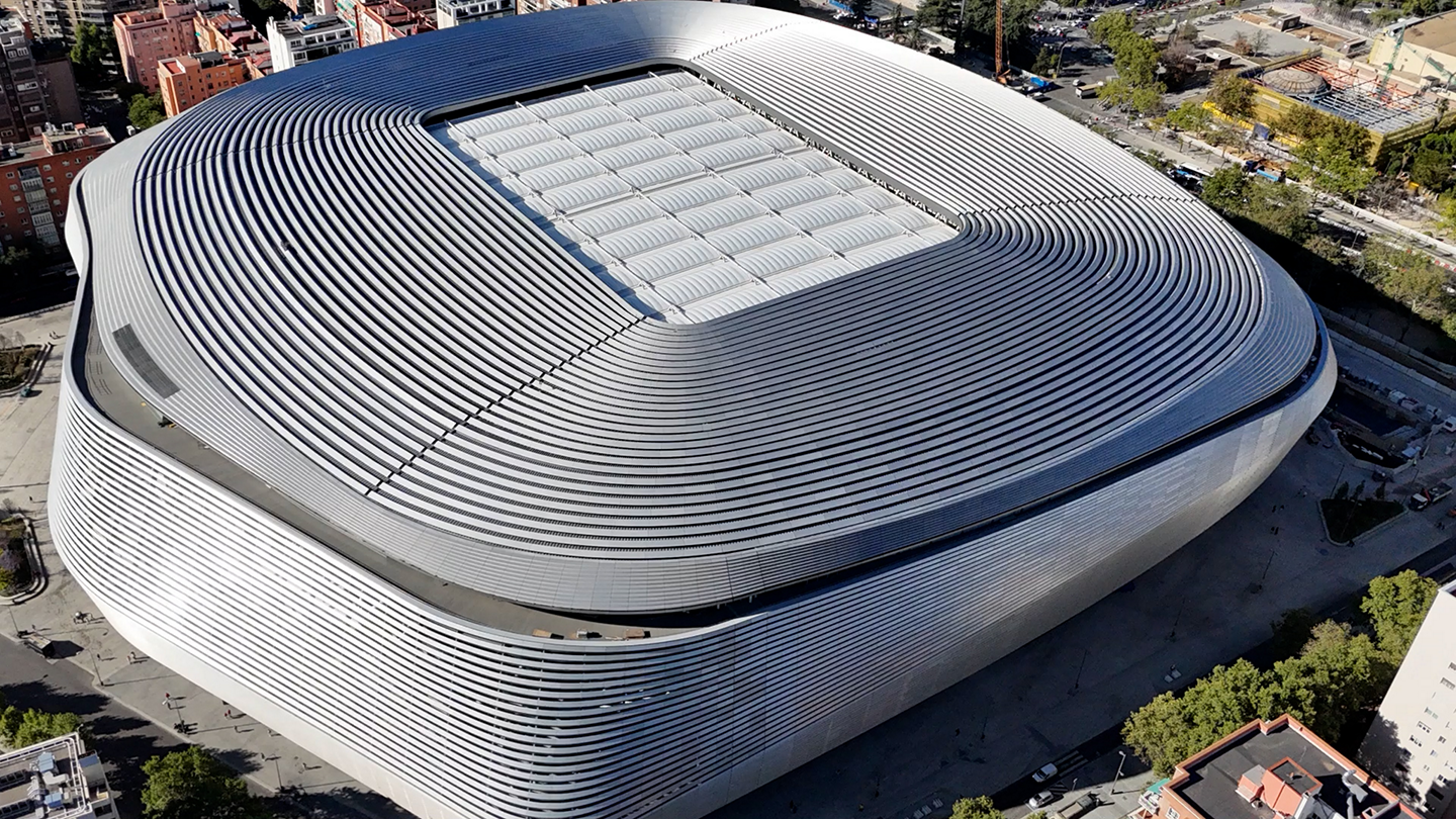 Widok stadionu Santiago Bernabéu z lotu ptaka z zakrzywionym metalowym dachem i otaczającym obszarem miejskim