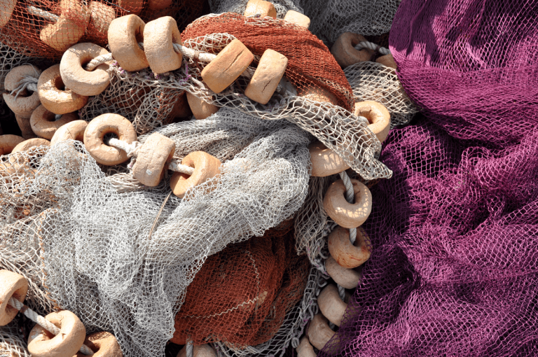 Close-up of colorful fishing nets with ring-shaped floats in purple, gray, and brown mesh