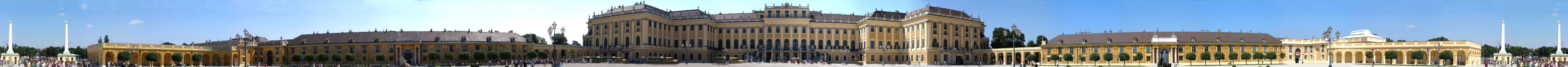Panoramic view of Schönbrunn Palace with its long golden facade and classical architecture under a blue sky