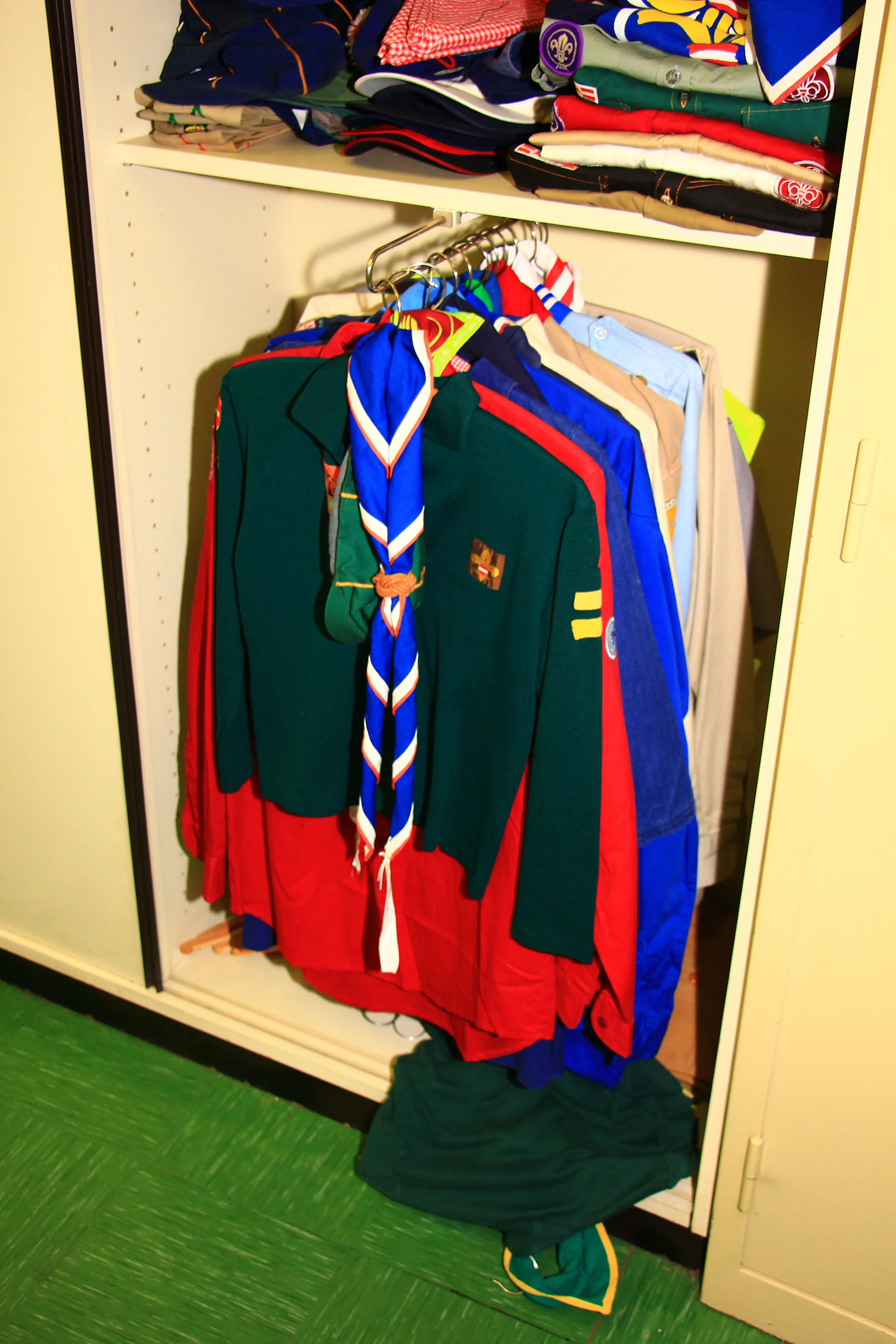 scouting uniforms and scarves hanging in a closet display