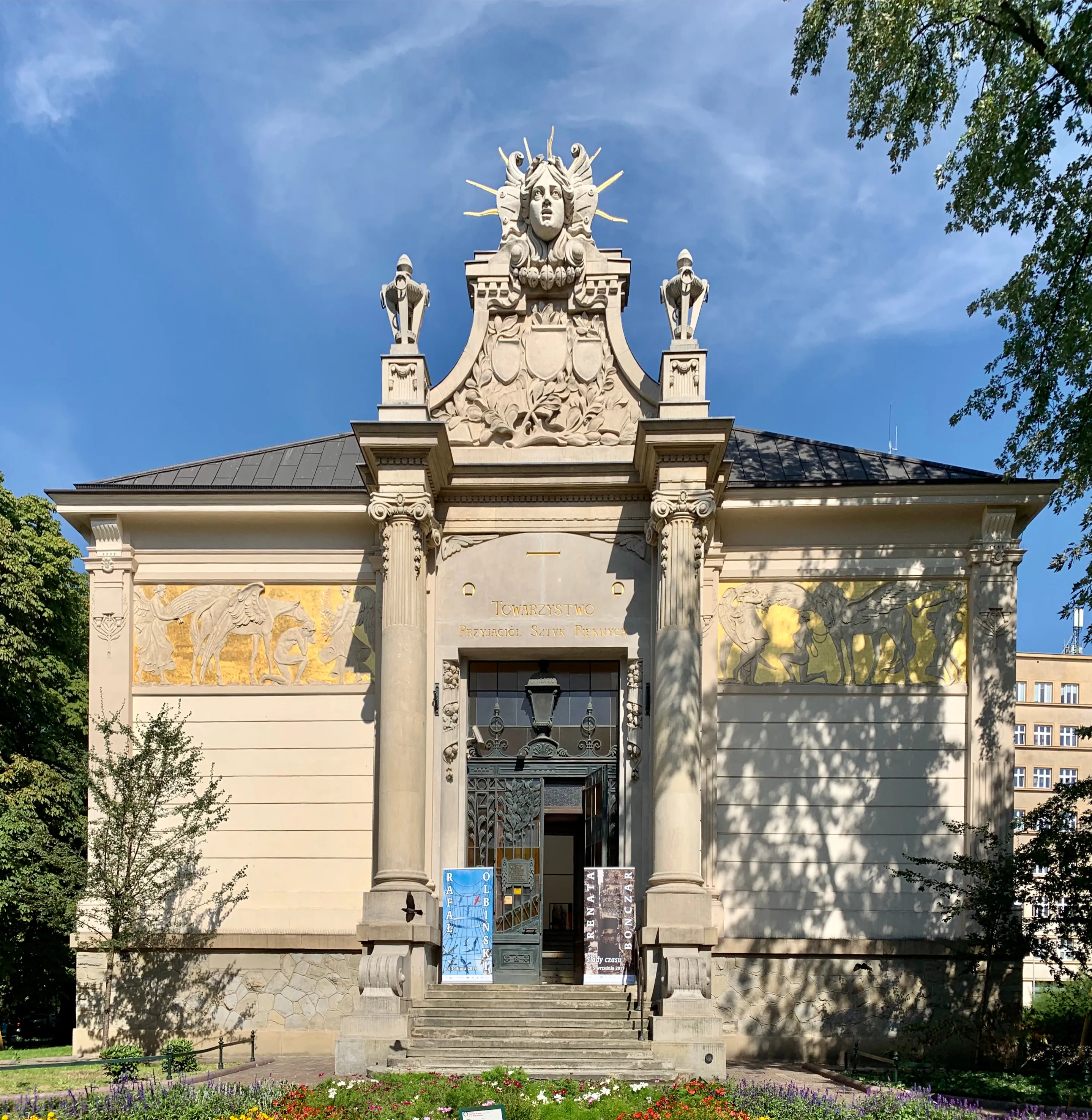 The Secession building with a decorative facade, columns, and a sculpture above the entrance under a blue sky