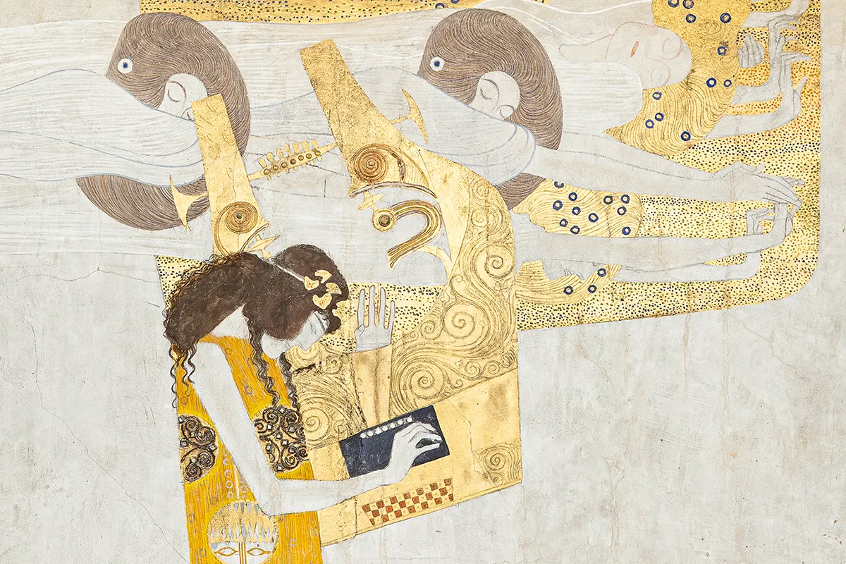 close-up of a golden art nouveau mural with intricate patterns and figures