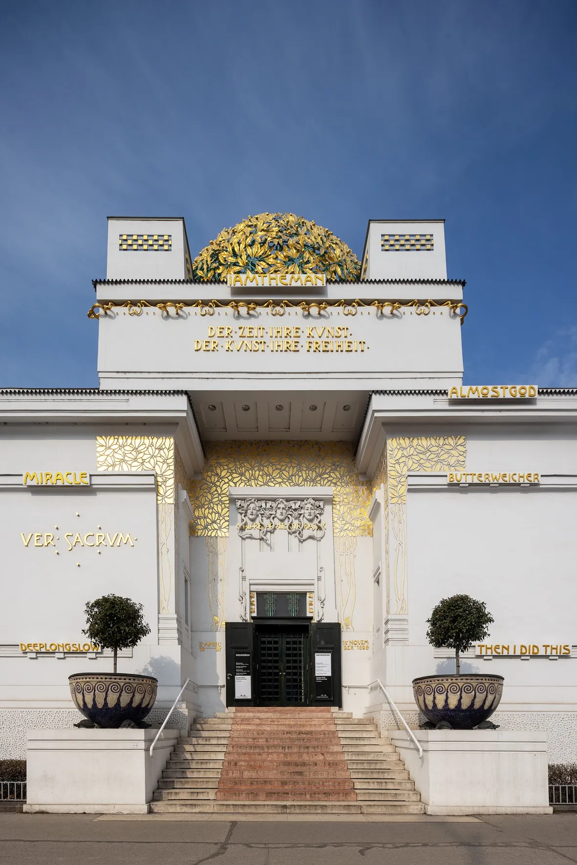 The Secession building with a white facade, gold ornate details, and a golden dome under a blue sky