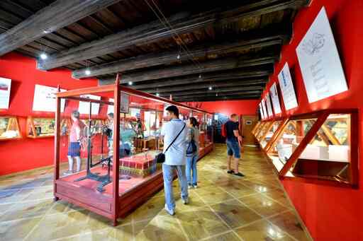 Interieur van het Sex Machines Museum met rode muren, houten balken en bezoekers die exposities in glazen vitrines bekijken