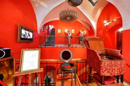 Interieur van een museum met rode muren, gewelfde plafonds en historische erotische artefacten op display