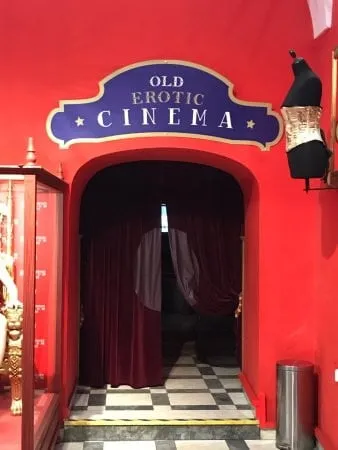 Entrada al Antiguo Cine Erótico con paredes rojas, un letrero azul y un suelo a cuadros