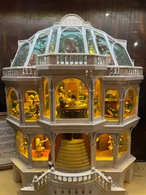 Een meerlaagse glazen en witte structuur met verlichte compartimenten die mechanische seksspeeltjes en beeldjes tonen.