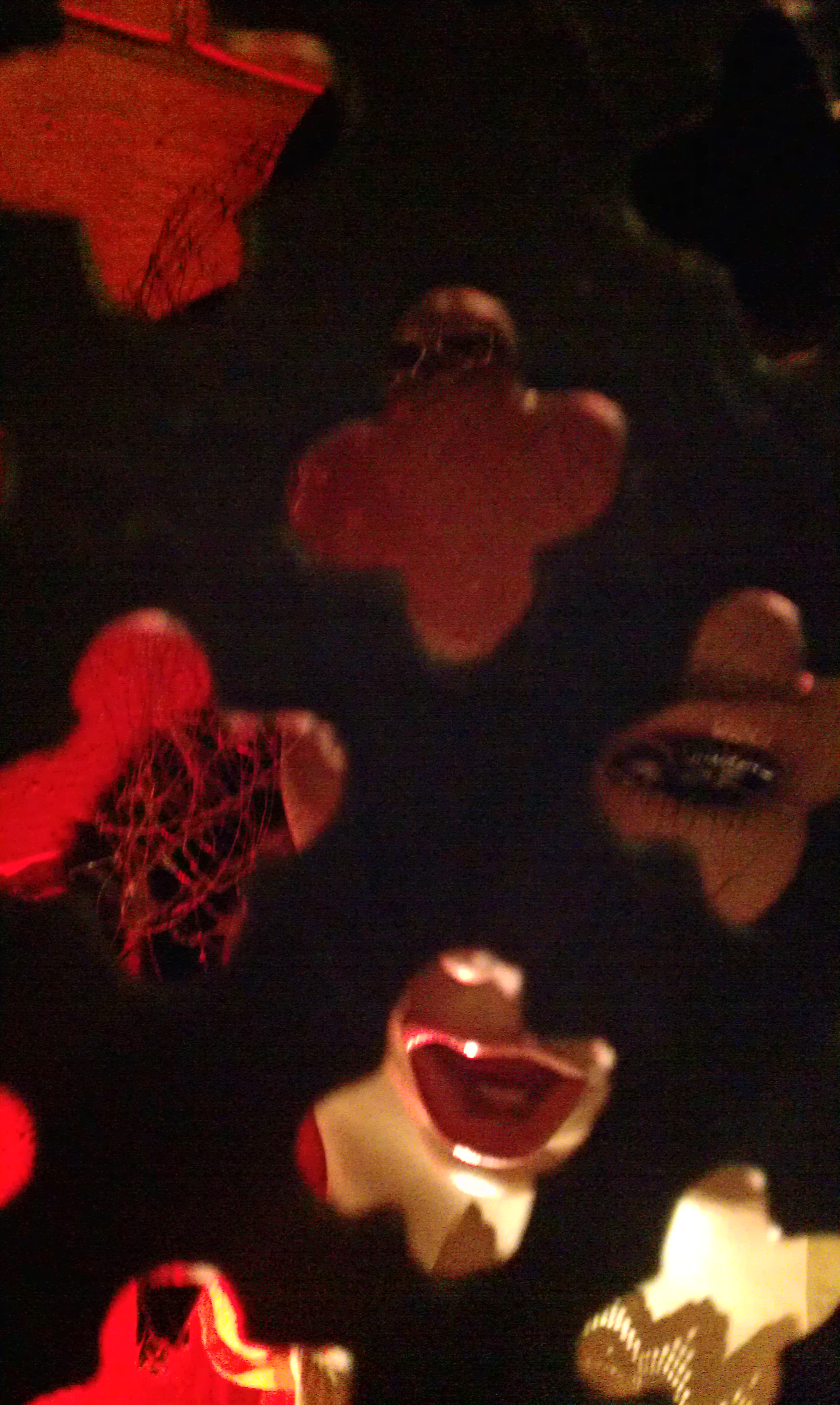 Illuminated cut-out figures with expressive faces and red lighting in a dimly lit exhibition space