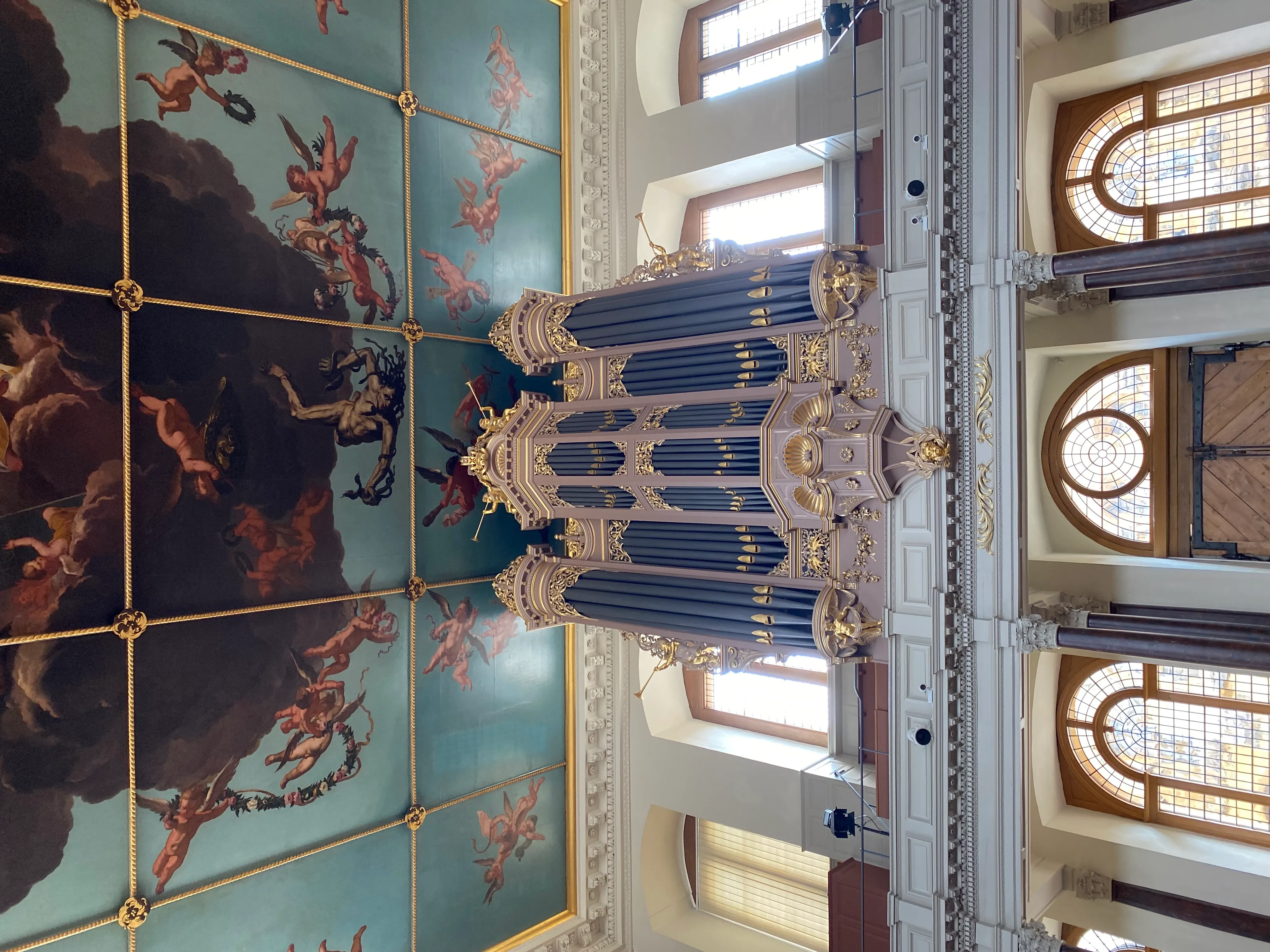 Vista interior del Sheldonian Theatre que muestra el ornamentado órgano de tubos y el techo pintado con figuras entre nubes.