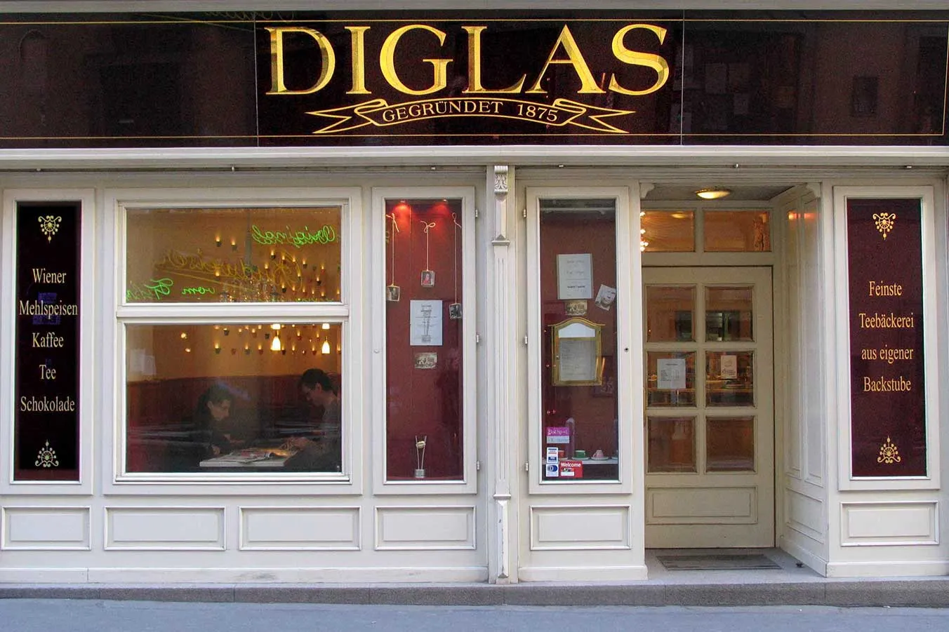 El exterior de Diglas, una histórica tienda vienesa con letras doradas en una fachada oscura y señalización tradicional en las ventanas.