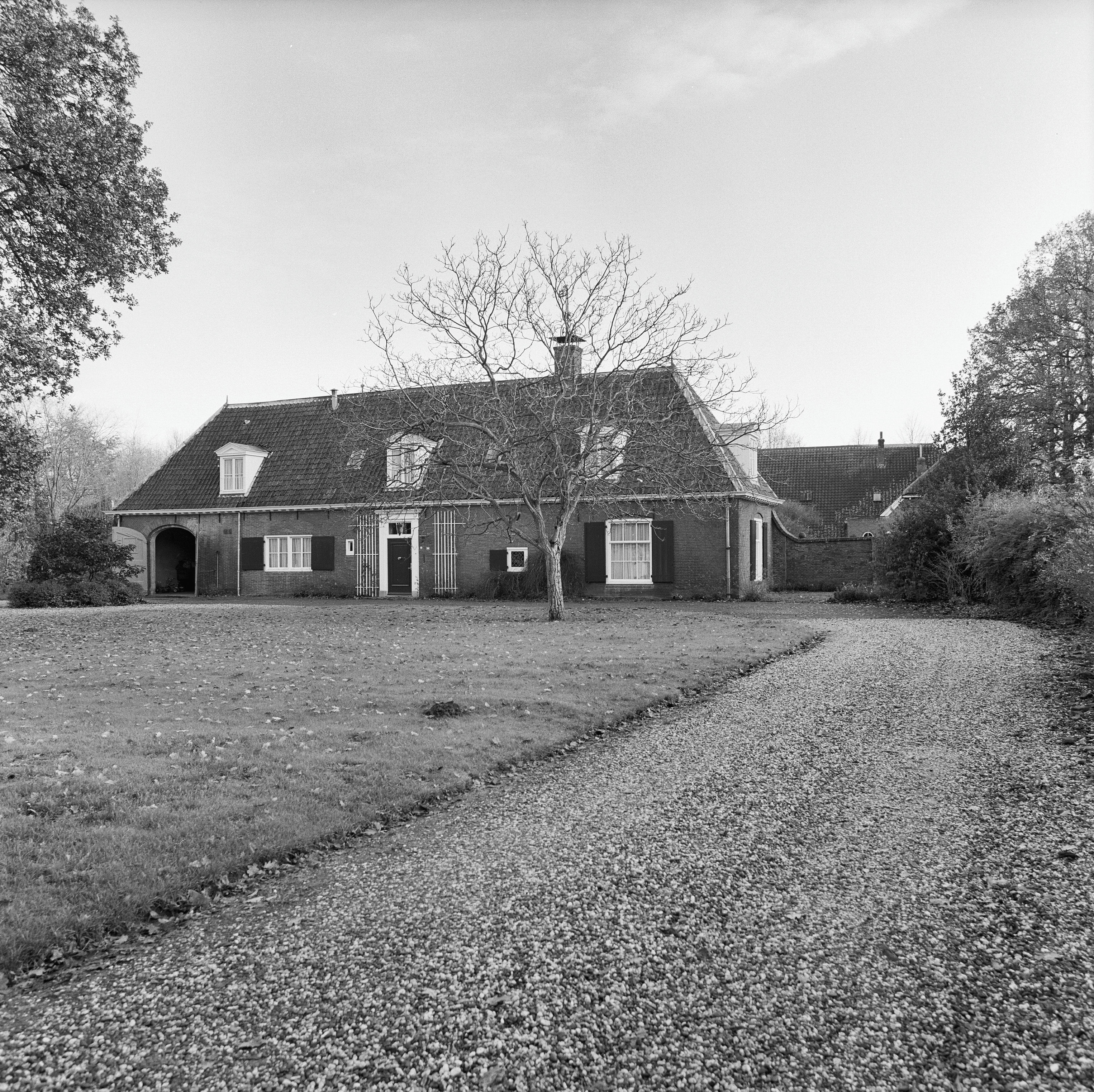 Black-and-white view of Slot Zuylen's historic brick facade with gabled roof, dormer windows, and central entrance surrounded by gravel path and trees