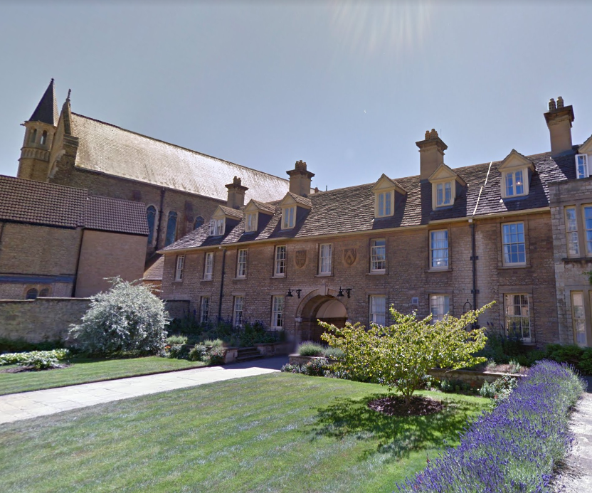 Kamienny dziedziniec Somerville College z przystrzyżonym trawnikiem, obwódką z lawendy oraz historycznymi budynkami z lukarnami i wieżą kaplicy w tle.