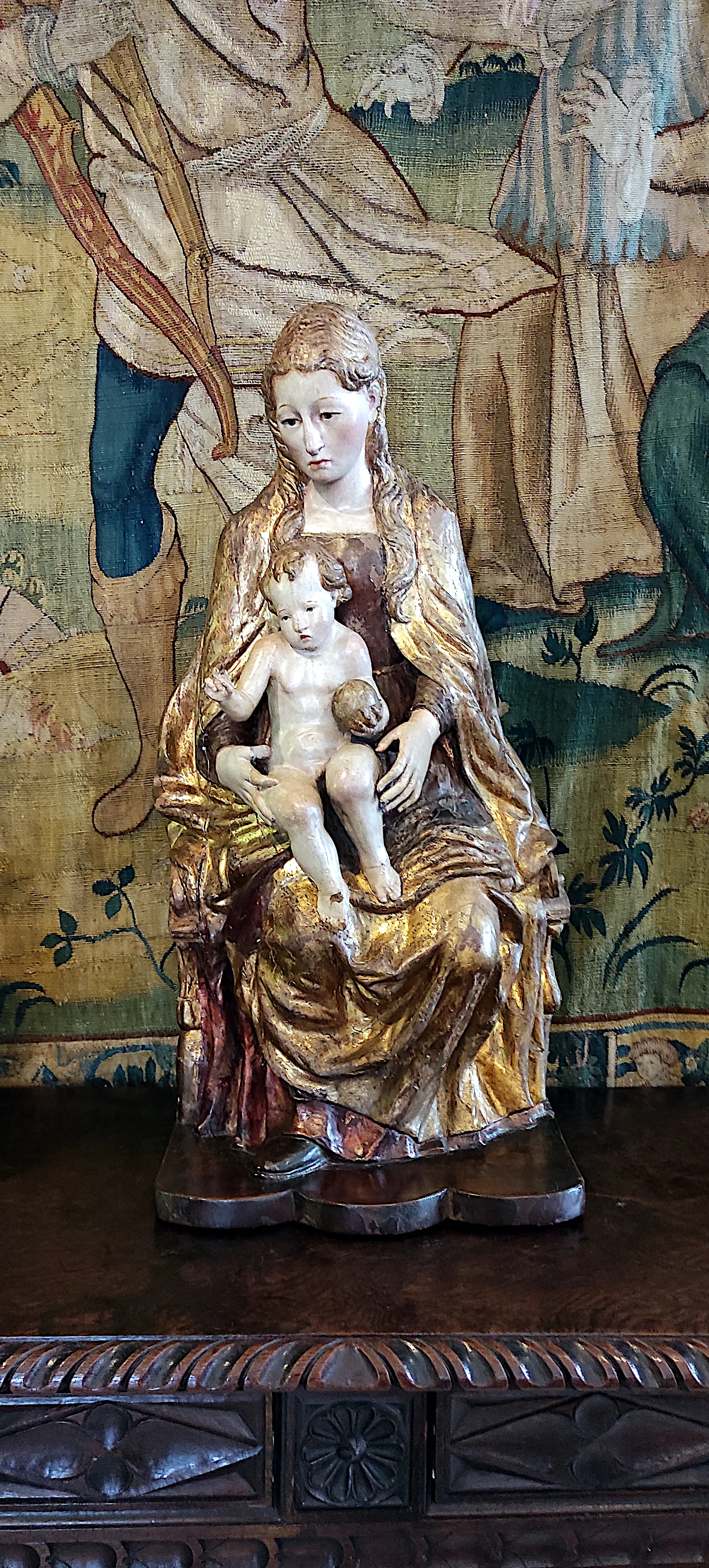 verguld houten beeld van de maagd maria met het kindje jezus op een gesneden houten kabinet