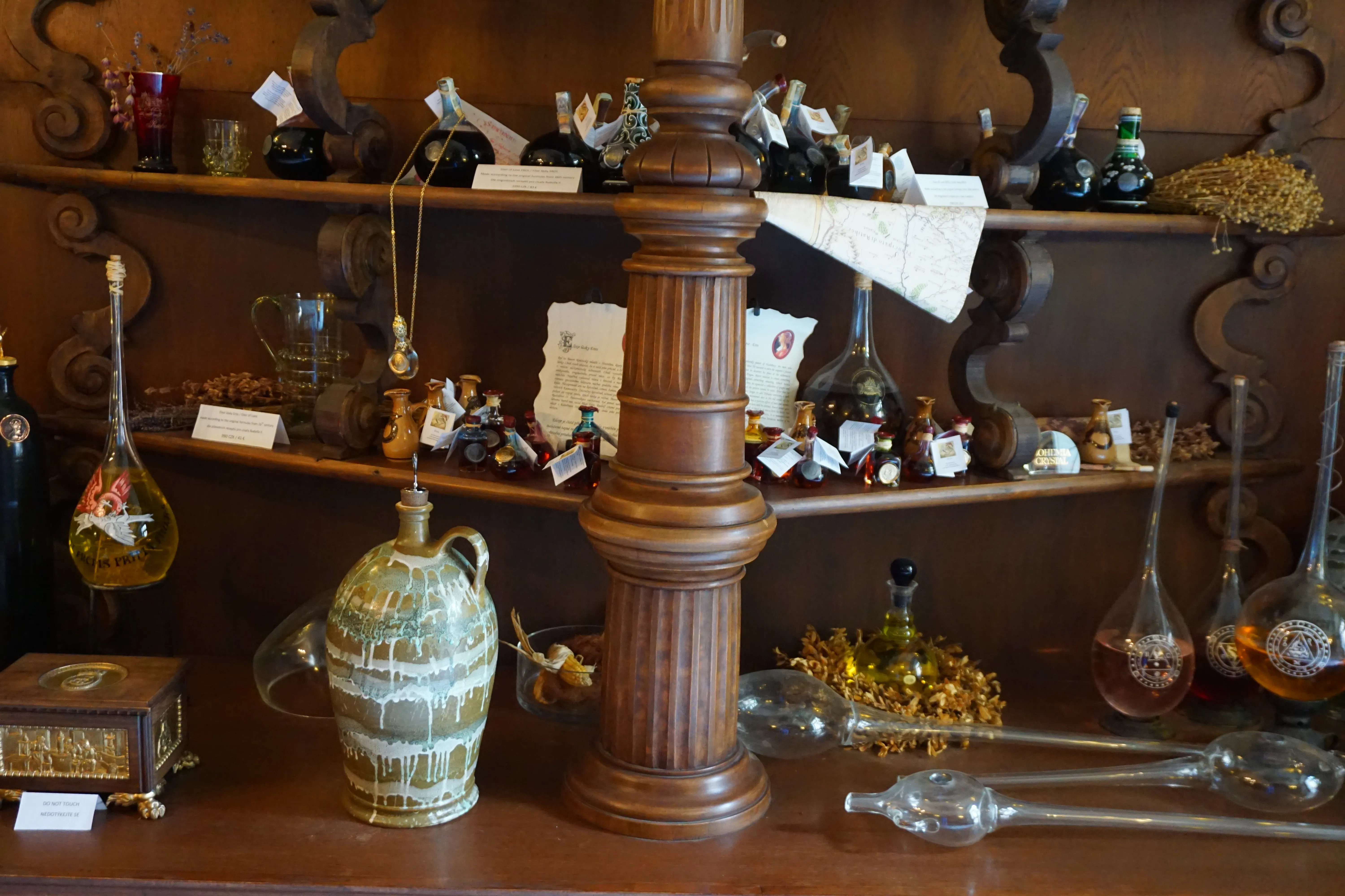 alchemical equipment including glass flasks, a ceramic still, and wooden shelves with various tools