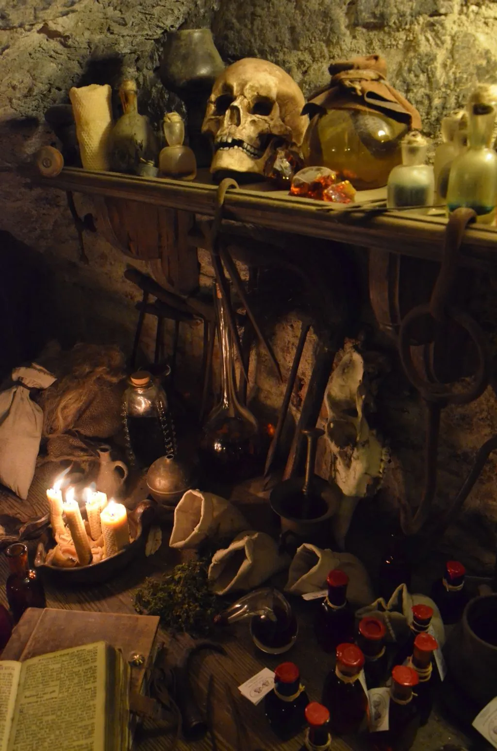 dimly lit alchemical laboratory with stone walls, skull, candles, and glass flasks