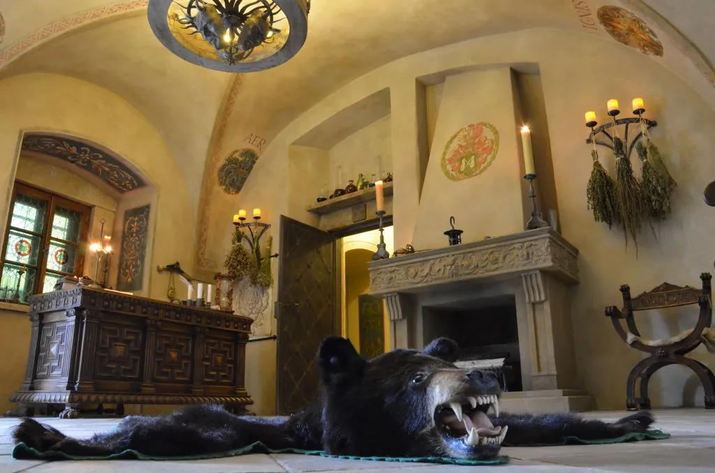 Interior of a recreated Renaissance alchemical laboratory with a taxidermy bear, fireplace, and ornate furniture
