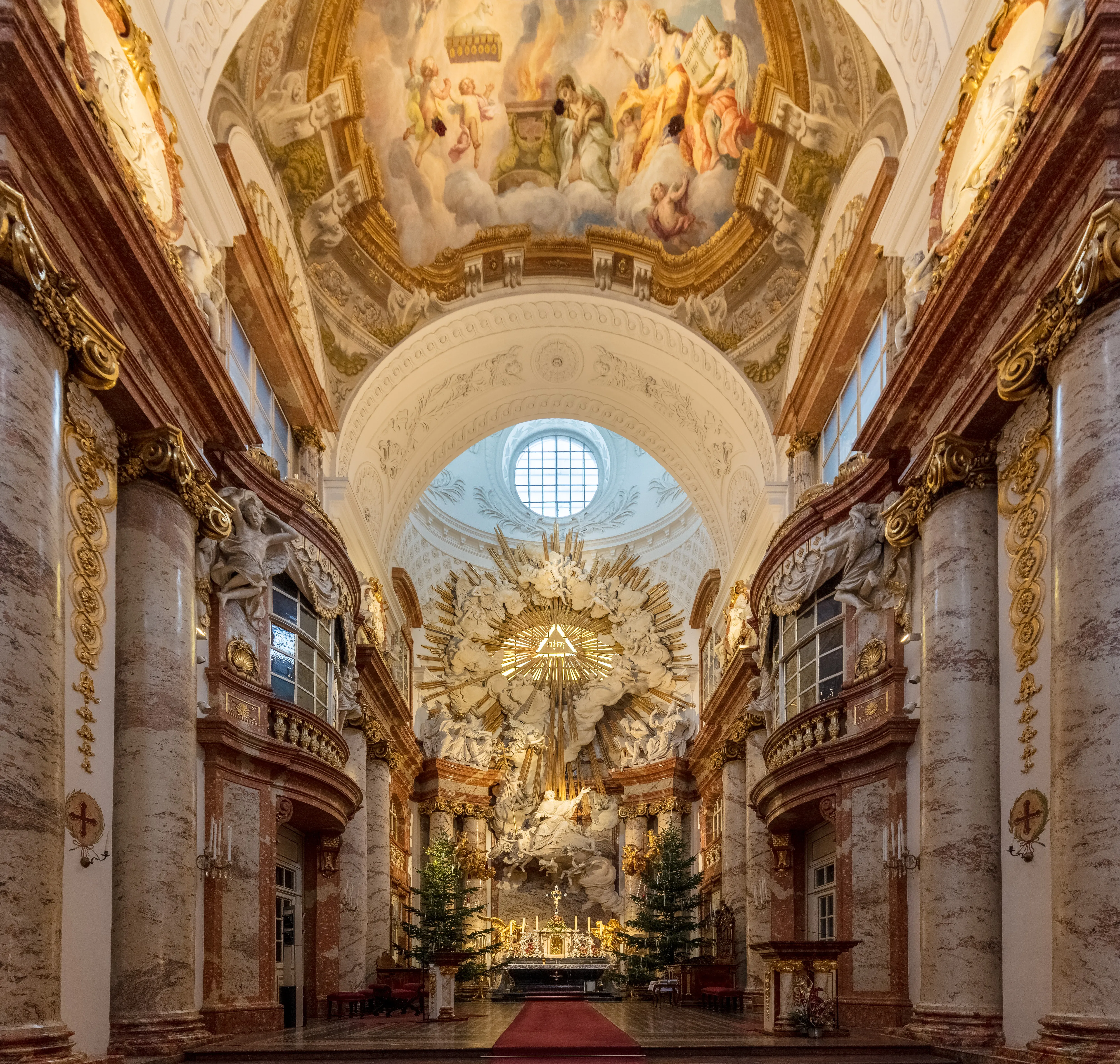 Interior of St. Charles Church with ornate baroque architecture, marble columns, golden details, and a large fresco on the ceiling