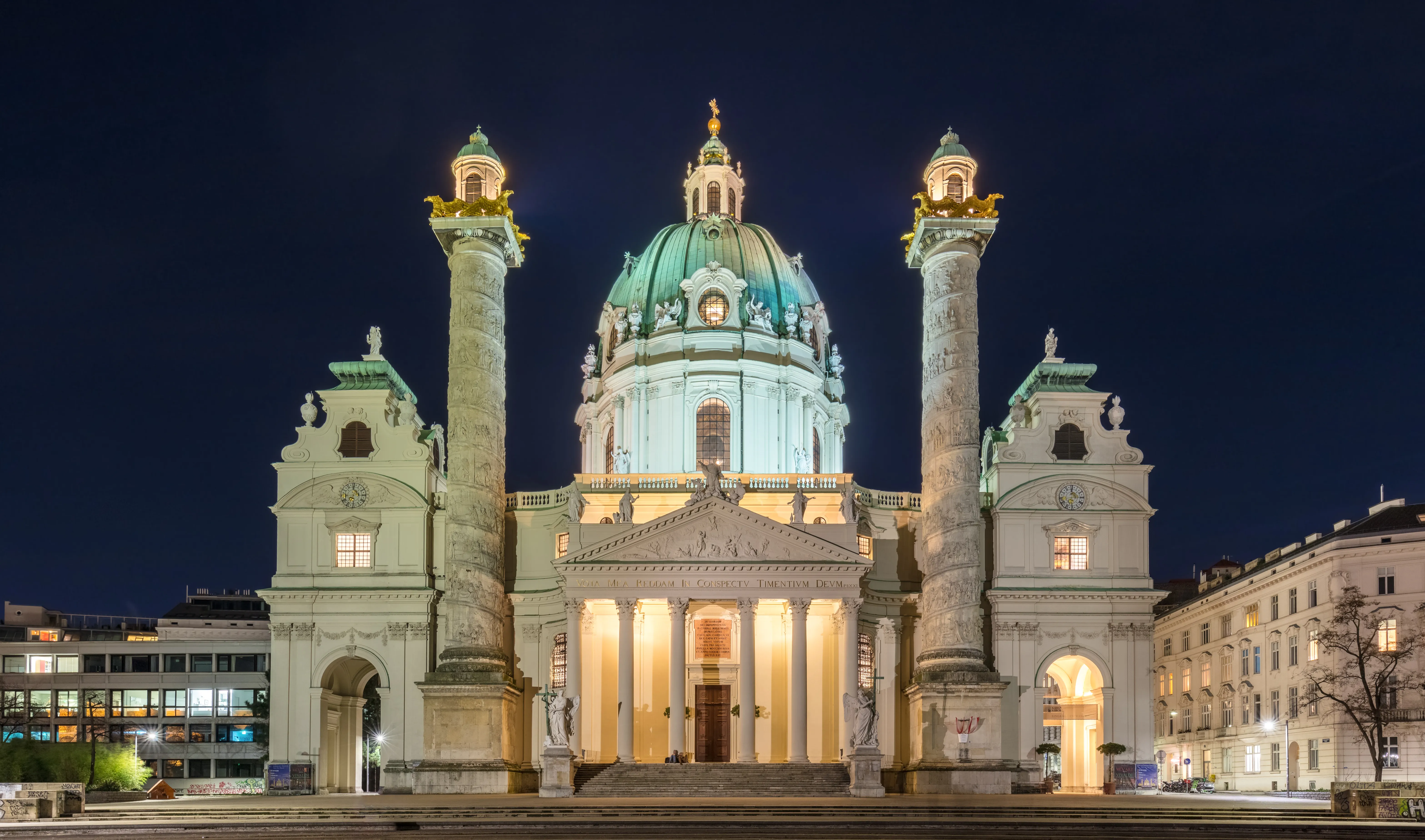 Iglesia de San Carlos por la noche con su cúpula verde y fachada iluminada