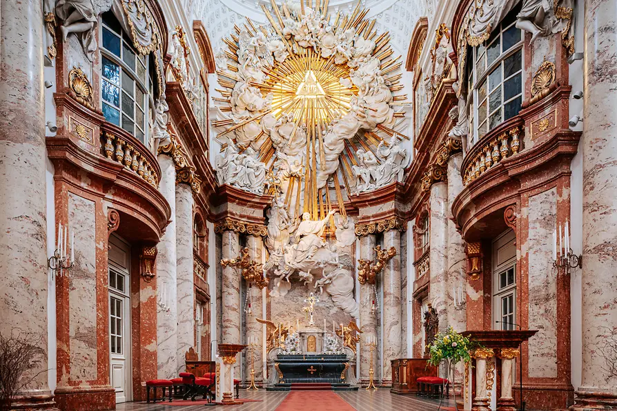 Interior de la Iglesia de San Carlos con ornamentada arquitectura barroca, un fresco dorado en el techo y columnas de mármol