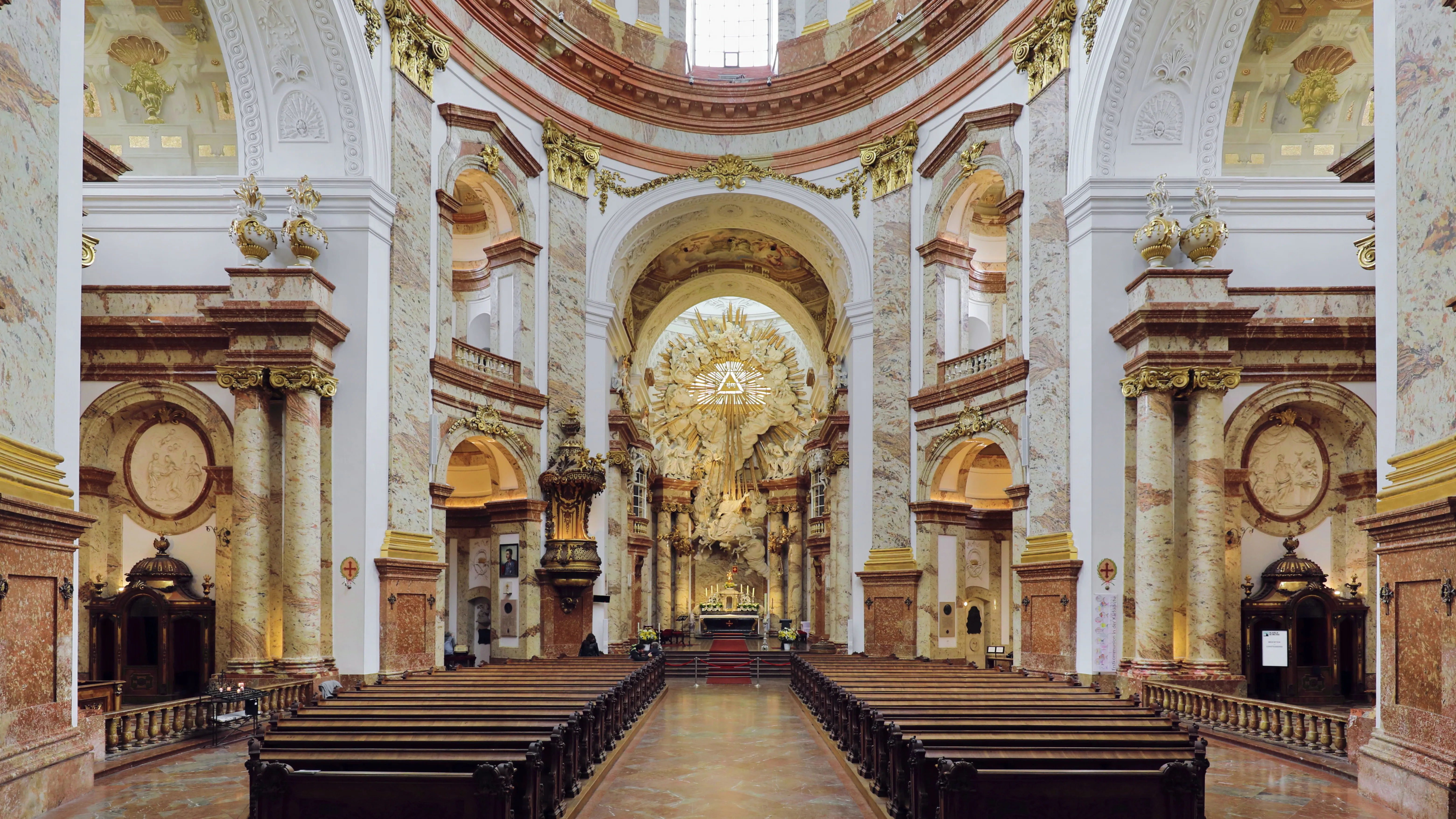 Vista interior de la Iglesia de San Carlos con columnas ornamentadas, un techo abovedado alto y bancos de madera