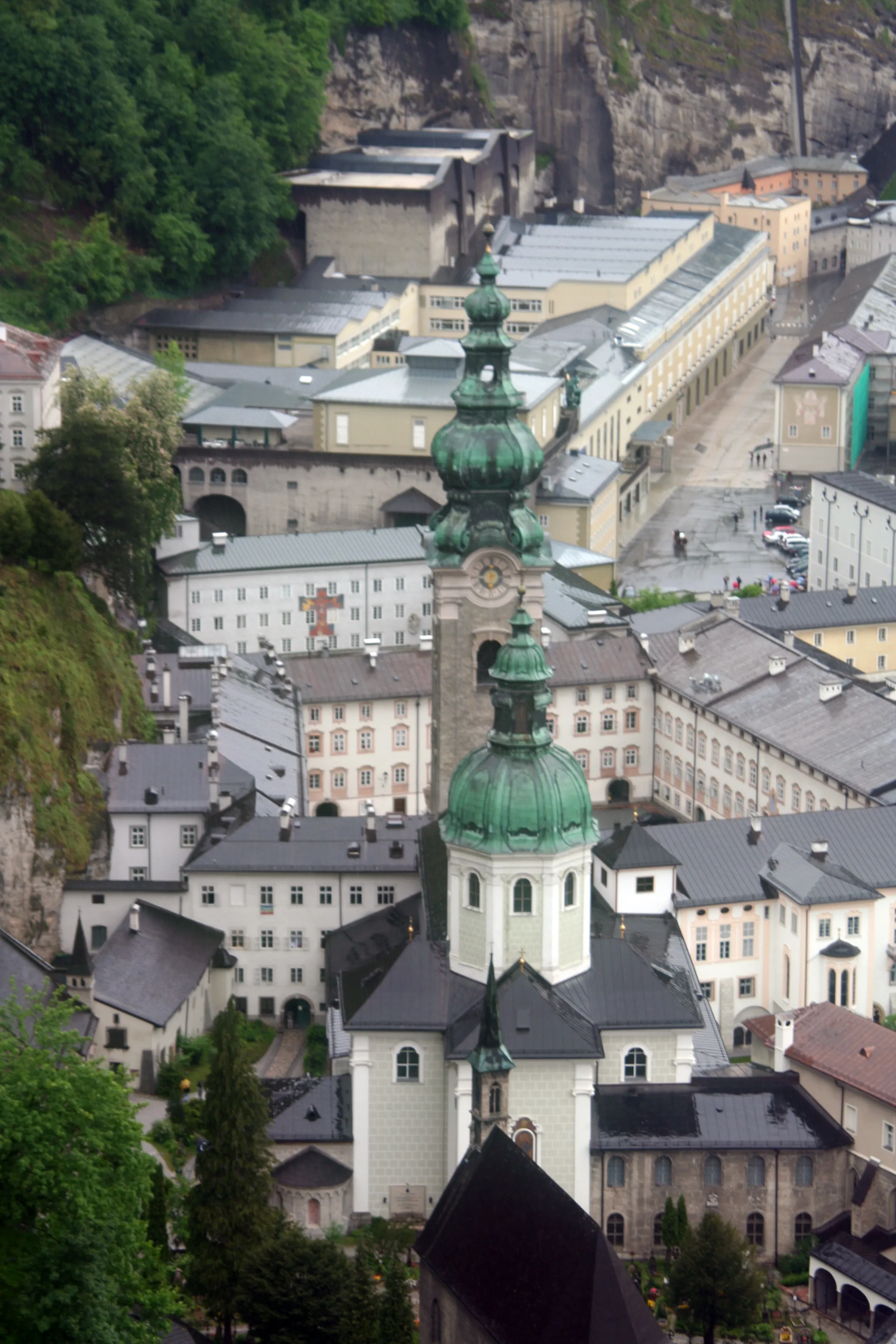 Widok z lotu ptaka na kościół opactwa św. Piotra z zielonymi barokowymi wieżami w kształcie cebuli, w otoczeniu zabudowań opactwa i ze skalistym klifem w tle