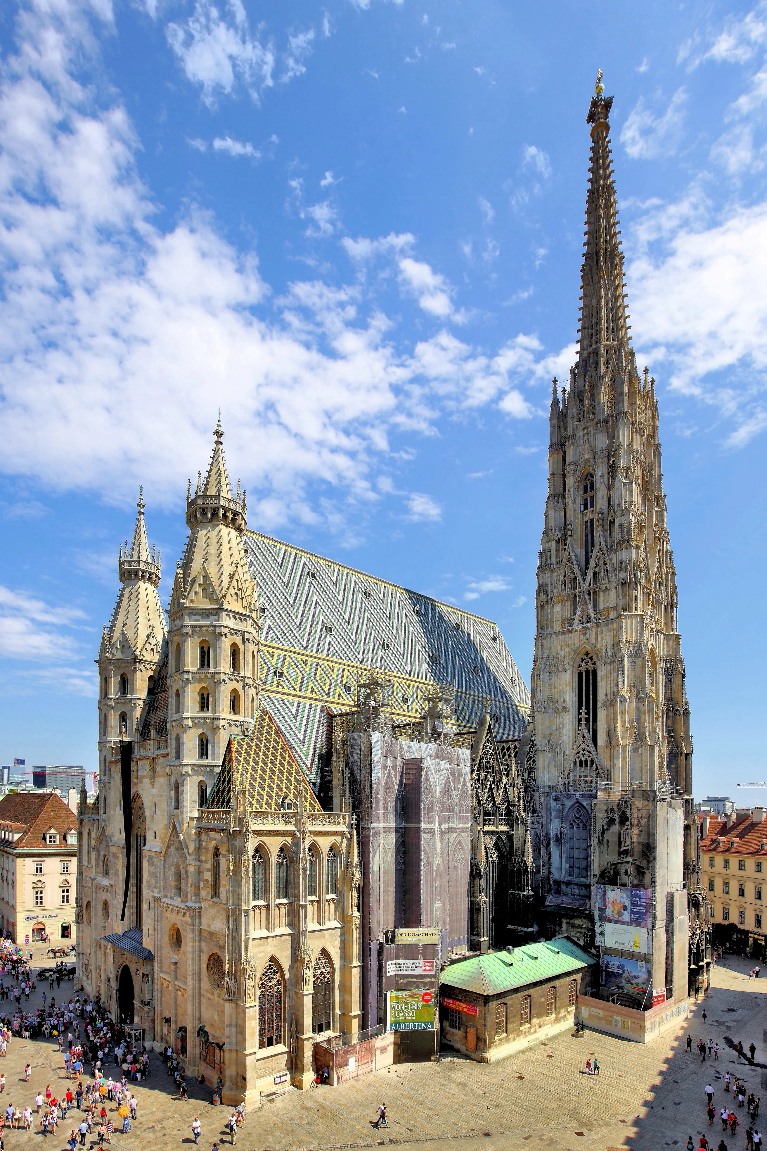 St. Stephen's Cathedral with its tall spire and patterned roof against a blue sky with scattered clouds