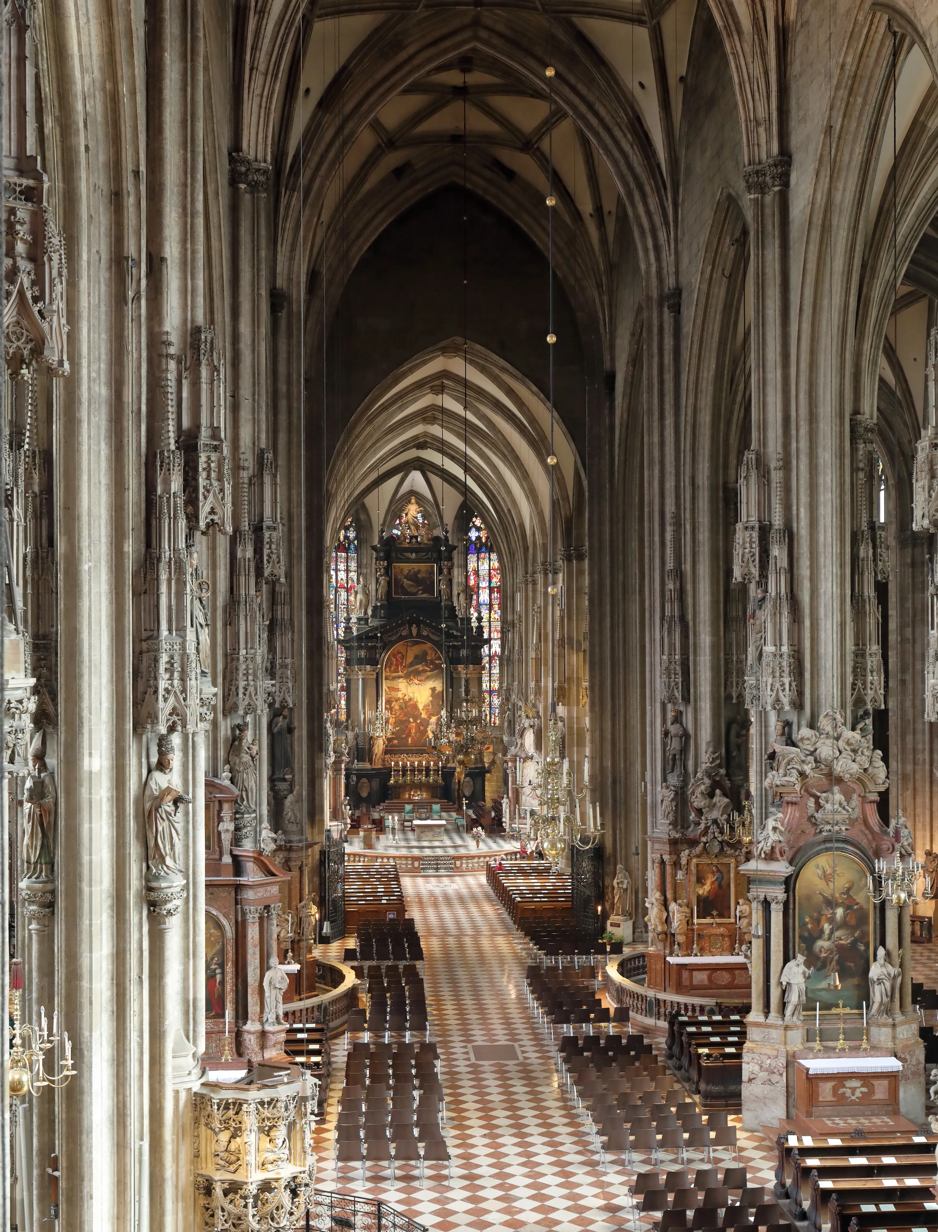 Interior of St. Stephen's Cathedral with high vaulted ceilings, stone pillars, and a checkered floor leading to the altar