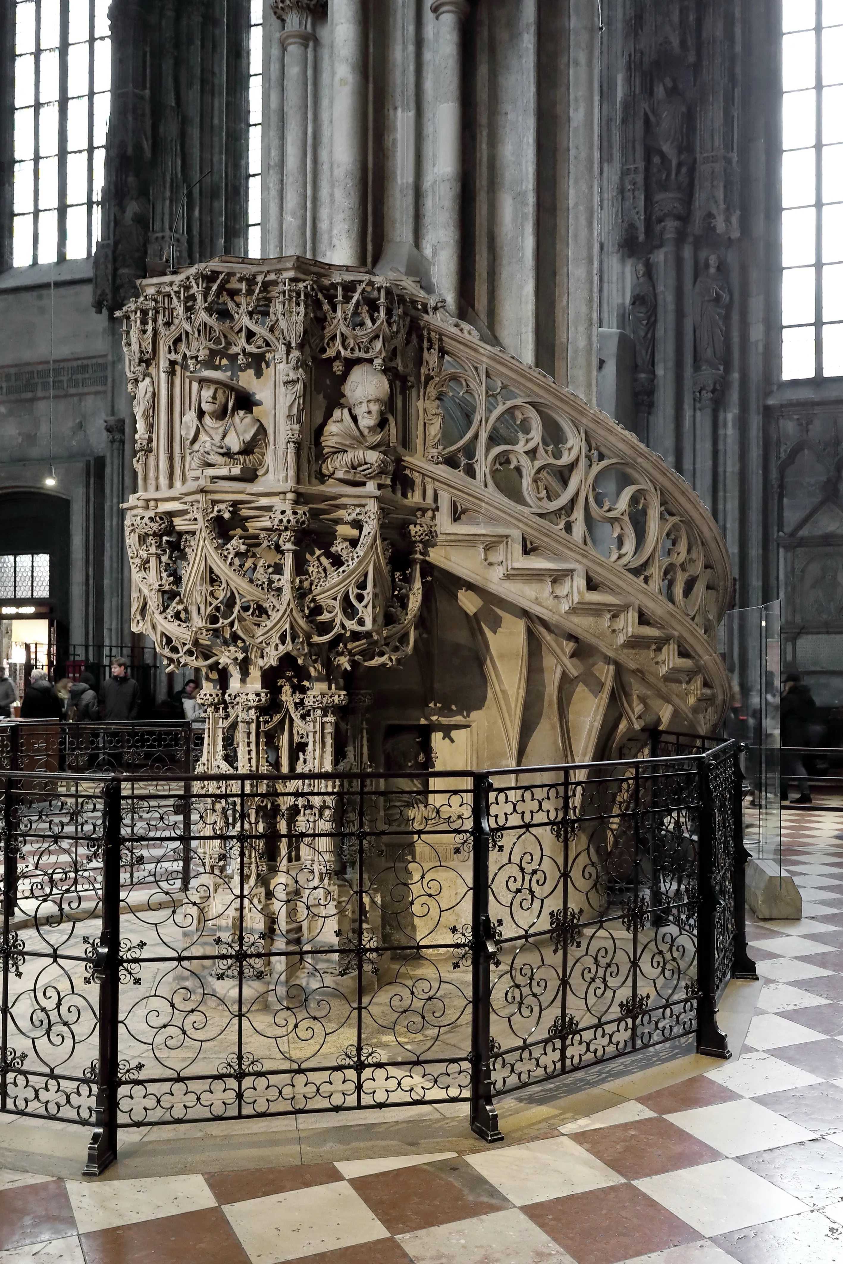 Ingewikkeld houten preekgestoelte met gesneden figuren en sierlijke details in een kathedraal met een dambordvloer en grote ramen